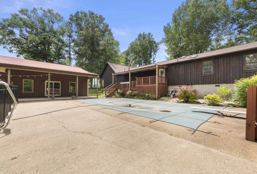 Expansive concrete patio area with an in-ground pool, covered with a safety net