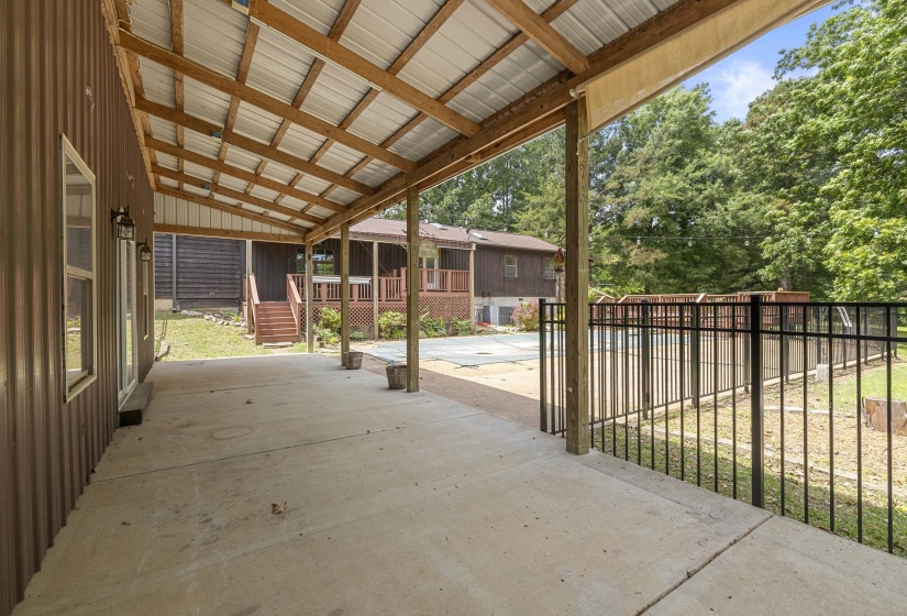 Expansive covered concrete patio with a wood-framed metal roof, offering an outdoor living area