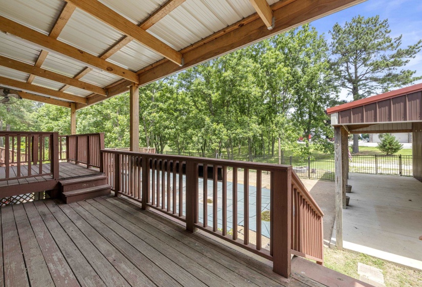 Expansive covered deck featuring wood decking, wood railings, and a corrugated metal roof