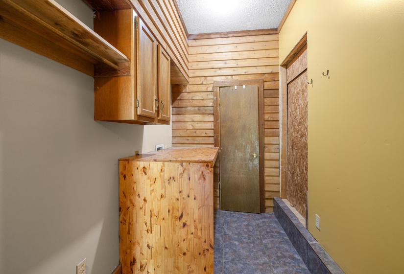 Utility space featuring wood-paneled walls and a wood-finish storage unit with integrated cabinetry
