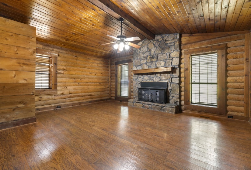 Spacious room with wood-finish flooring, log walls, and a wood plank ceiling