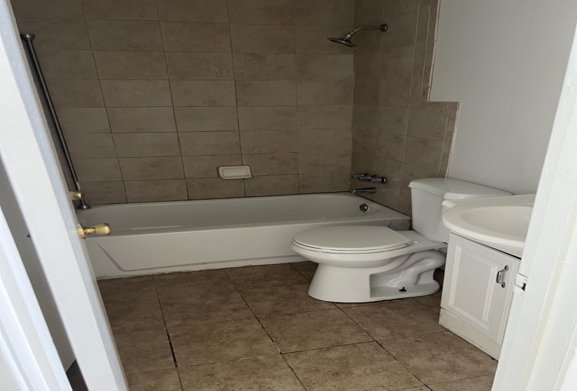 Full bathroom featuring a white bathtub, ceramic tile surround, and a coordinating floor