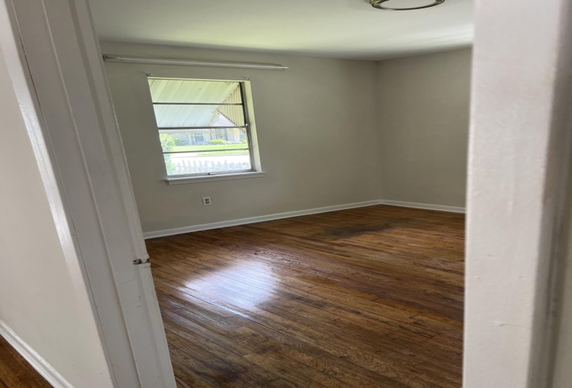 Interior room featuring wood-finish flooring, light-toned walls, and a window with a white frame