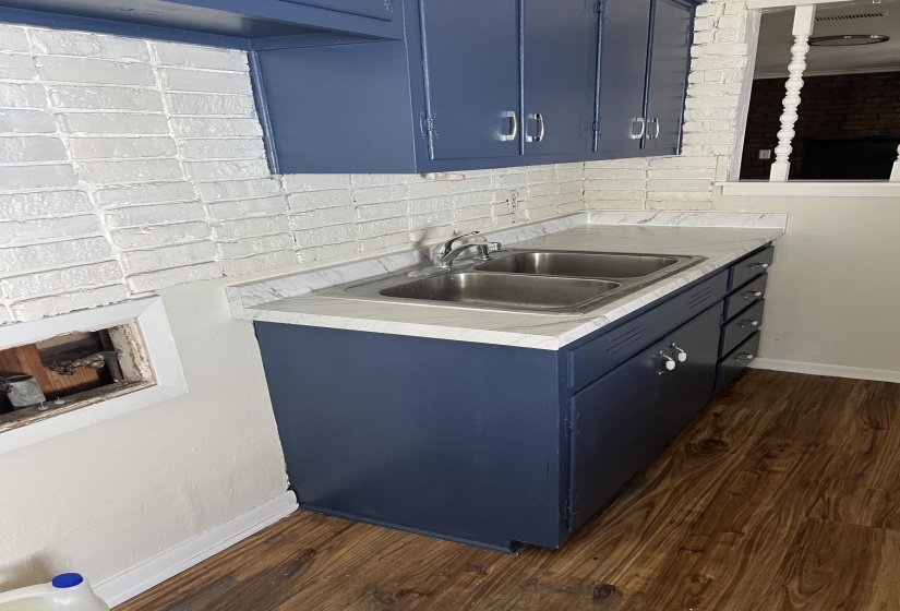 Kitchenette featuring a double stainless steel sink, wood-finish flooring, and blue cabinetry with brushed nickel hardware