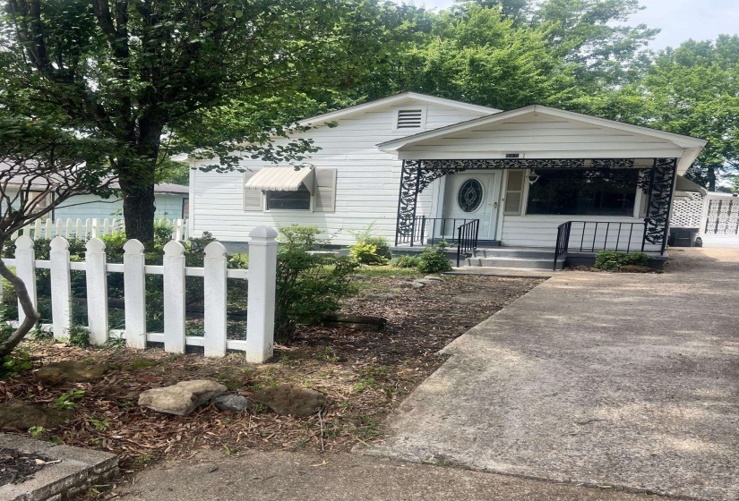 White exterior with a covered front porch featuring decorative ironwork