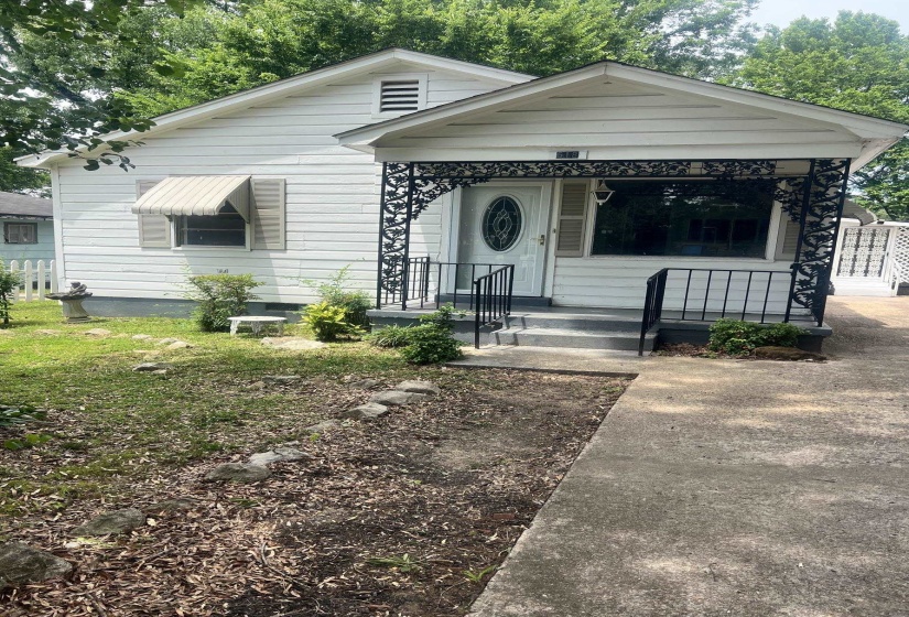 White siding exterior featuring a covered porch with intricate black wrought iron detailing