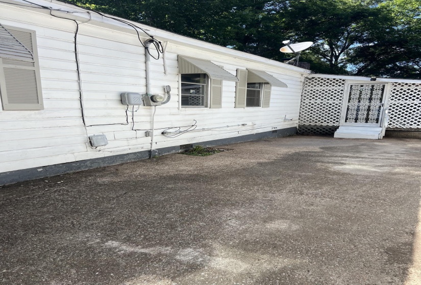 White siding exterior with louvered window shutters and awnings, featuring a latticework screen enclosure with an ornamental security door
