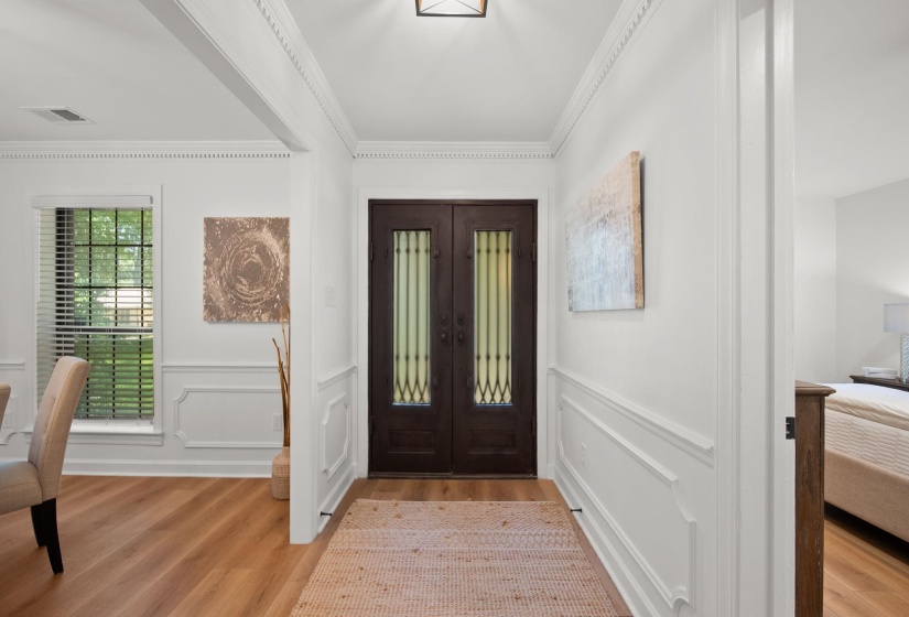 Entryway featuring rich wood-finish double doors with glass inserts, wood-finish flooring, decorative wainscoting, crown molding, and a square ceiling light fixture