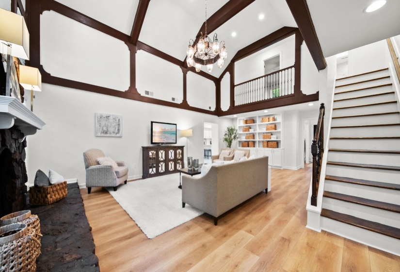 Vaulted living space featuring exposed ceiling beams and light wood-finish flooring