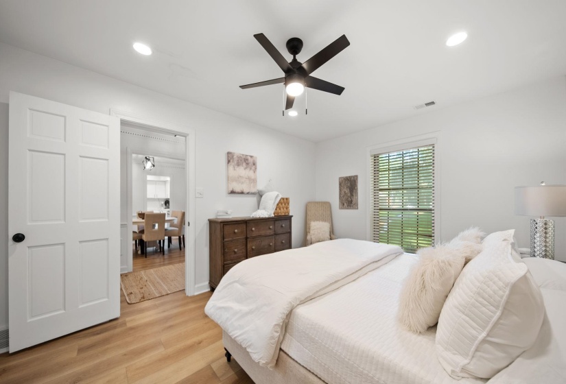Spacious room featuring wood-finish flooring, a contemporary ceiling fan, recessed lighting, white six-panel doors, and a window with blinds