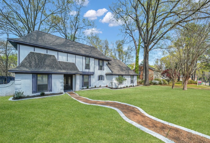 Rear view of property featuring roof with shingles, a lawn, and brick siding