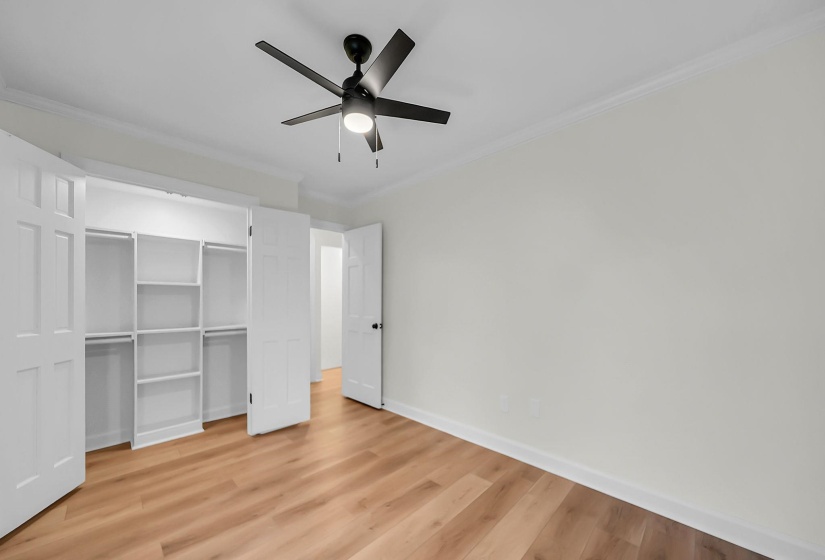 Unfurnished bedroom featuring light wood-type flooring, ornamental molding, a closet, and ceiling fan