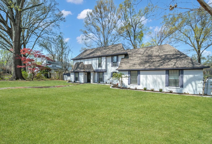 View of front of property featuring a front yard, roof with shingles, and brick siding