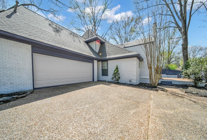 View of side of home featuring brick siding, driveway, roof with shingles, and a garage