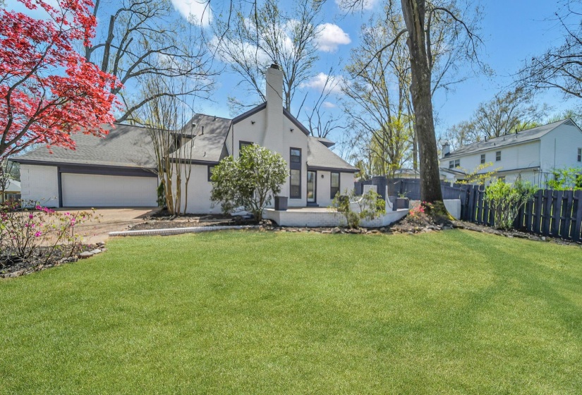 Rear view of house featuring stucco siding, a chimney, driveway, and a garage