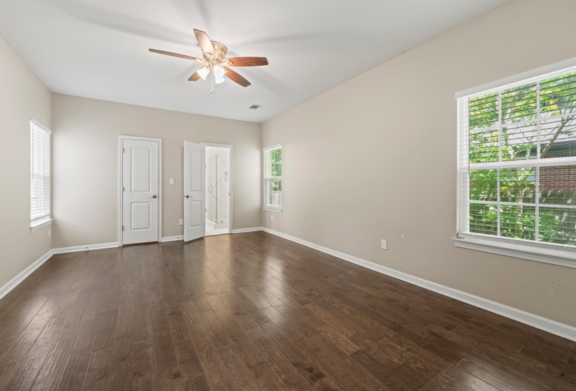 Spacious interior room featuring wood-finish flooring, light-colored walls, and a ceiling fan