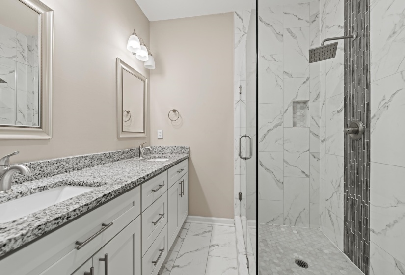Bathroom featuring a dual vanity with granite countertop, white cabinetry, and brushed nickel hardware