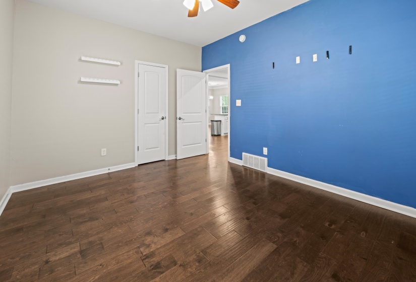 Room with wood-finish flooring, two panel doors, and a ceiling fan