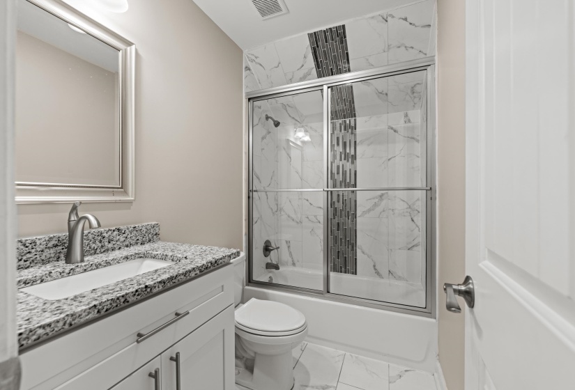 Bathroom featuring a white vanity with granite-style countertop, undermount sink, and brushed nickel faucet