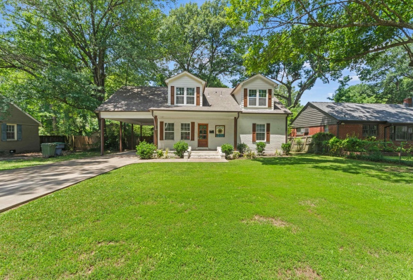White exterior with dark brown shutters, a covered porch, and dormer windows