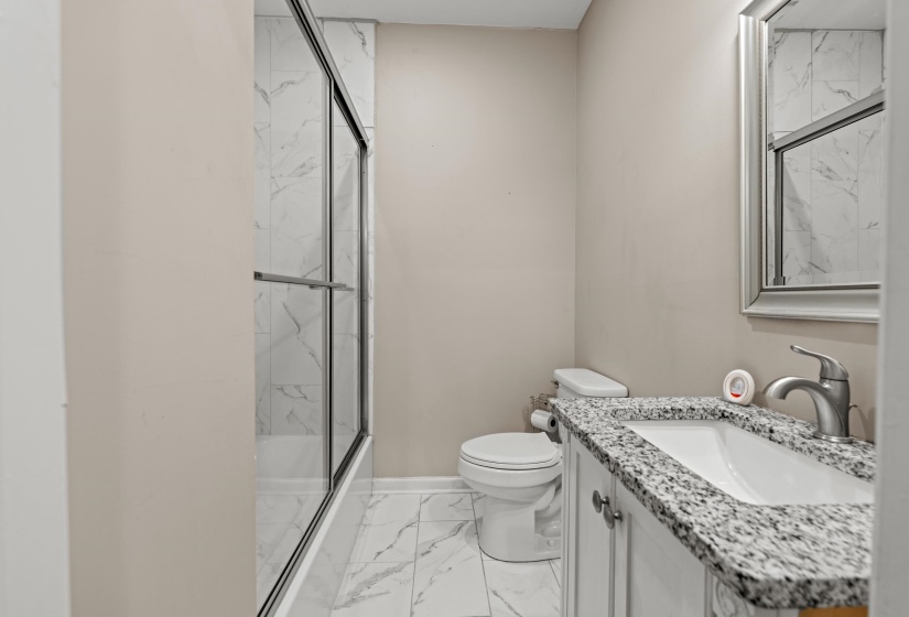 Bathroom featuring a white vanity with a speckled countertop, a rectangular undermount sink, and a framed mirror