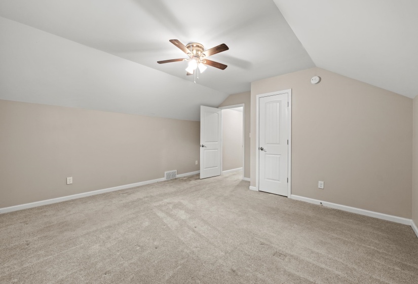 Carpeted room featuring a ceiling fan with integrated lighting, white trim work, and two paneled doors with brushed nickel hardware