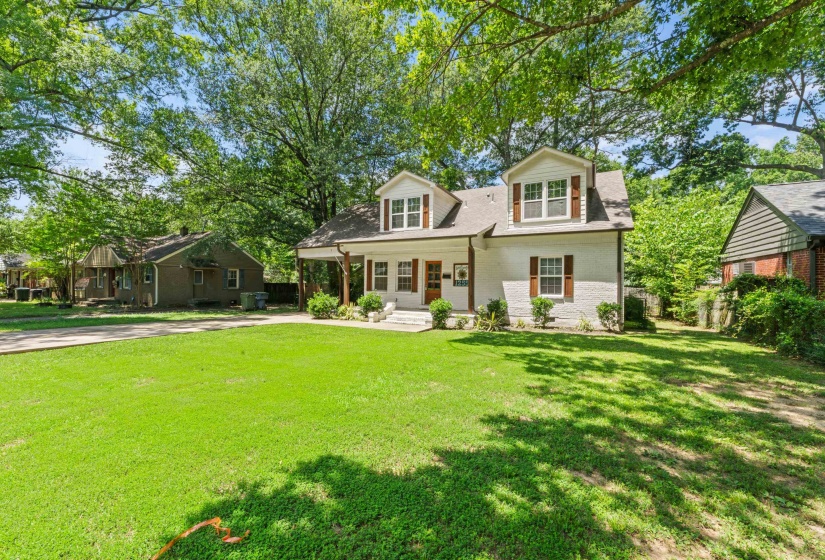 Dormer-style residence featuring a covered front porch with substantial columns, white brick exterior, and brown window shutters