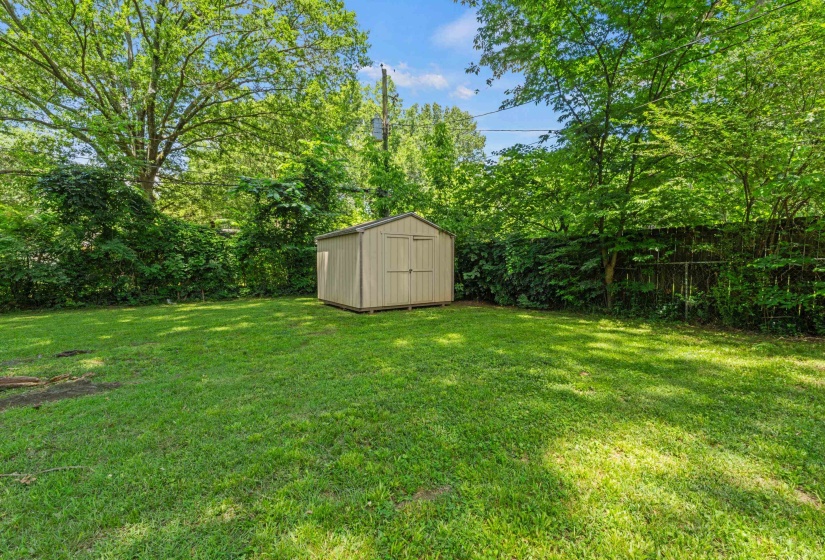 Expansive green lawn featuring a storage shed with a gabled roof and double doors