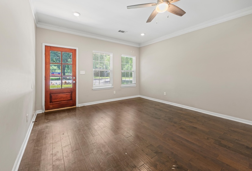 Entry area featuring a paneled wood door with glass inserts, wood-finish flooring, and crown molding