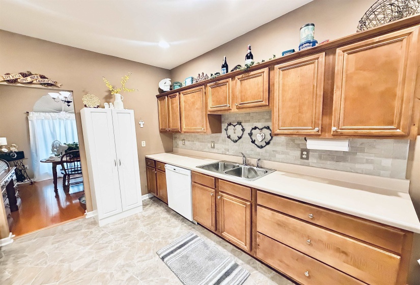 Kitchen featuring light wood cabinetry, a dual basin stainless steel sink, and a light-toned countertop