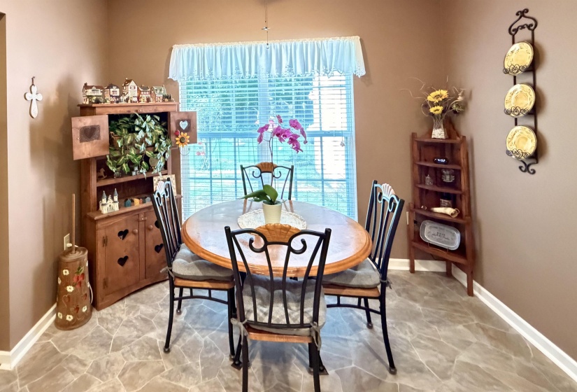 Dining space featuring patterned floor tiling, a large window with horizontal blinds, and a light valance