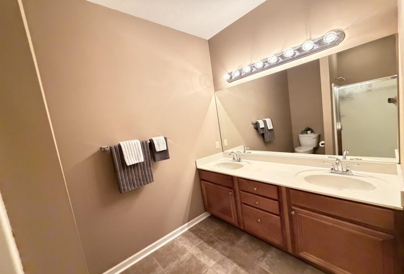 Double vanity with integrated sinks, wood-finish cabinetry, and a full-width mirror