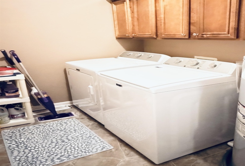 Dedicated laundry area with tile flooring and wood-finish cabinetry