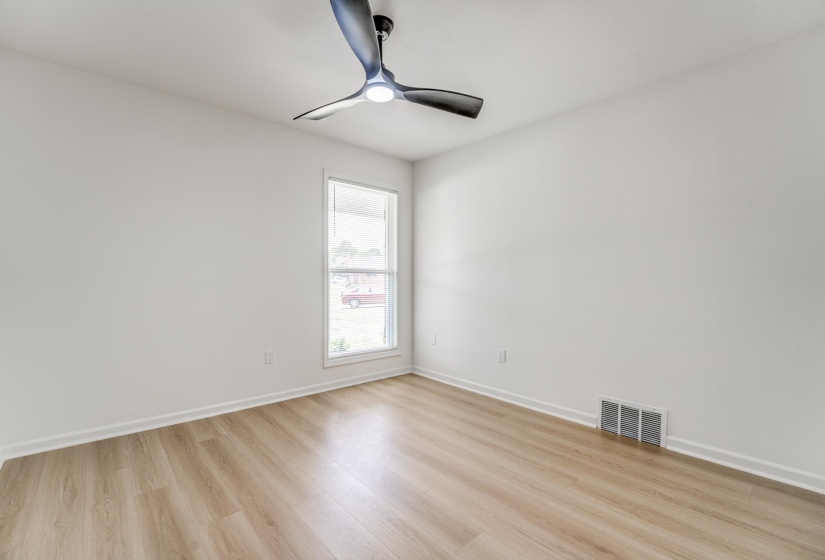 Bright room featuring light wood-finish flooring, white baseboards, and a modern ceiling fan with integrated lighting