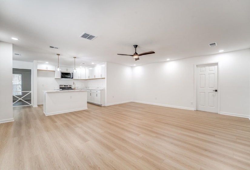 Open-concept living area featuring light wood-finish flooring, recessed lighting, and a contemporary ceiling fan
