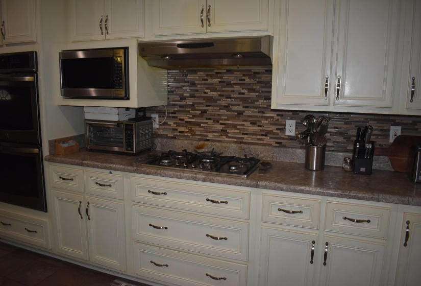 Kitchen featuring light-toned cabinetry, a mosaic tile backsplash, a built-in oven, and a gas cooktop