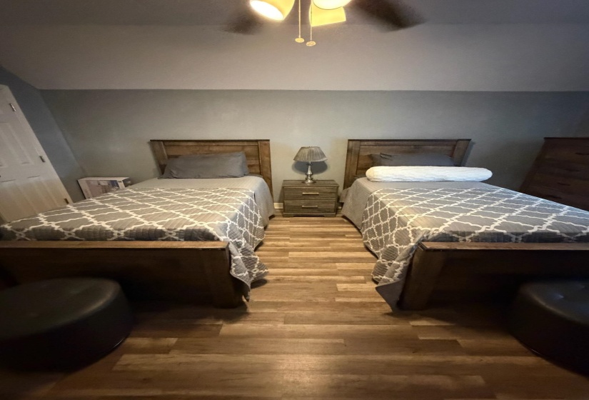 Bedroom featuring wood-finish flooring, a ceiling fan with light fixture, and light gray wall paint