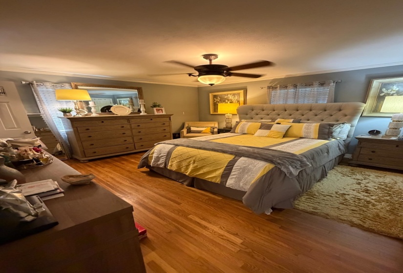 Hardwood flooring throughout the room, complemented by a ceiling fan with integrated lighting
