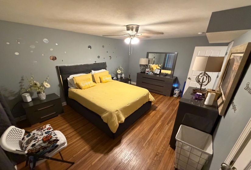 Bedroom featuring wood-finish flooring, a ceiling fan with integrated lighting, and light blue wall tones