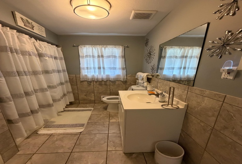 Bathroom featuring a single vanity with an integrated sink, floor-to-ceiling wall mirror, and tiled flooring