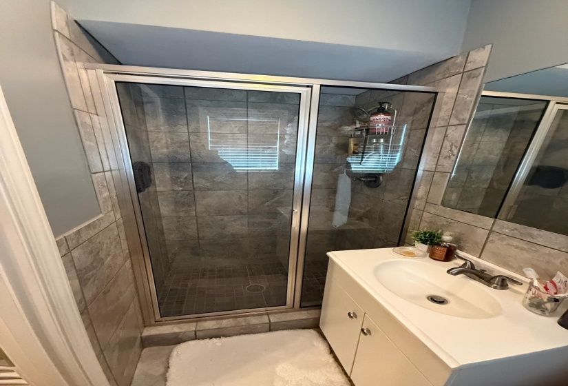 Enclosed shower with sliding glass doors and tiled walls