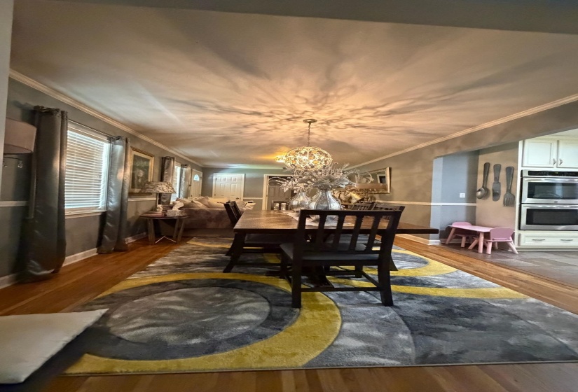 Dining area featuring wood-finish flooring, crown molding, and a decorative ceiling light fixture