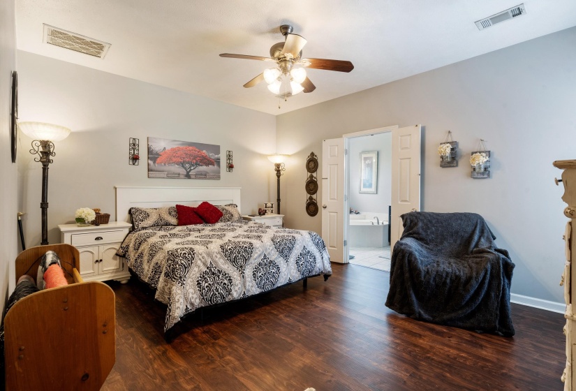 Spacious room featuring wood-finish flooring, light-colored walls, and a ceiling fan with integrated lighting