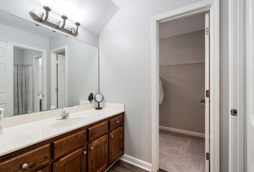 Full vanity featuring a single basin sink, white countertop, and wood-finish cabinetry