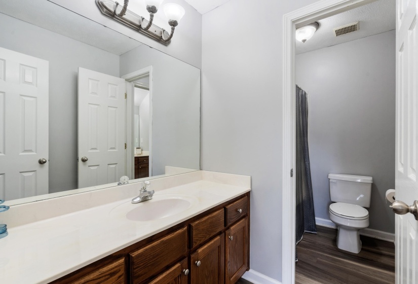 Bathroom featuring a wood-finish vanity with a light-colored countertop and an integrated sink