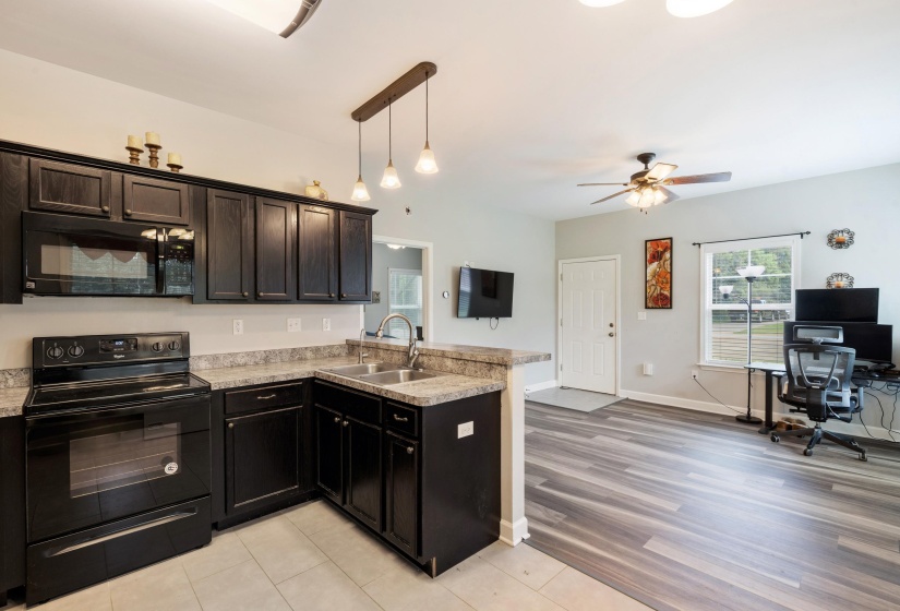 Modern kitchen featuring black cabinetry, light-toned countertops, and a full suite of black appliances