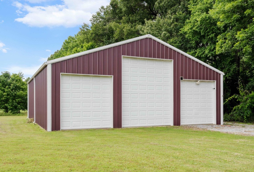 Metal construction outbuilding featuring three white overhead garage doors