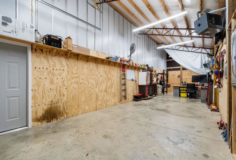 Spacious interior featuring metal-clad walls, exposed wooden roof trusses, and concrete flooring
