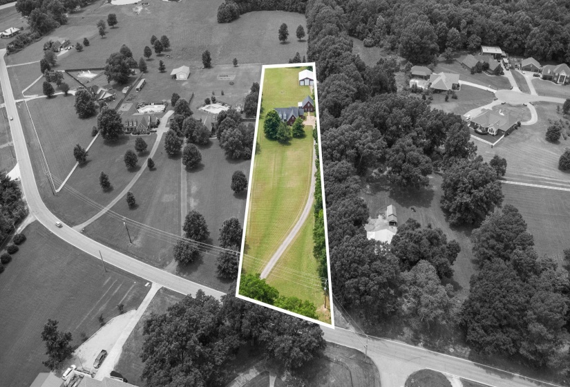 Expansive green lot featuring a long private driveway, a main residence, and an auxiliary structure