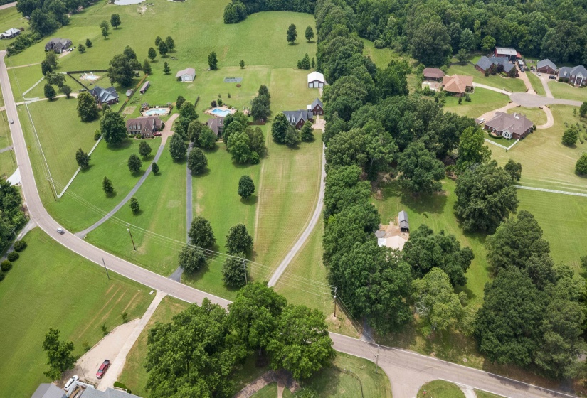 Expansive green landscape with scattered mature trees and paved roadways
